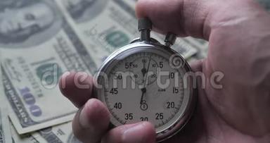 特写一个人在金钱背景上启动秒表。 时间就是金钱。 最后期限概念。